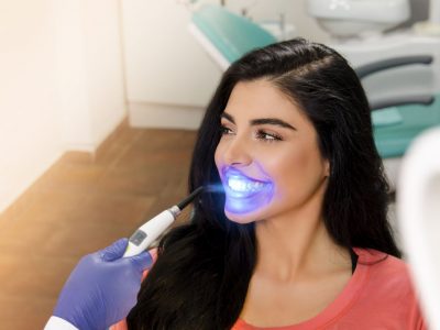 Gorgeous young woman UV lamp teeth whitening treatment